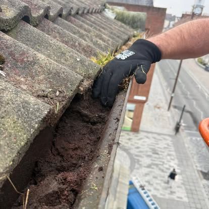 Vegetation being removed by hand from a blocked masonry gutter