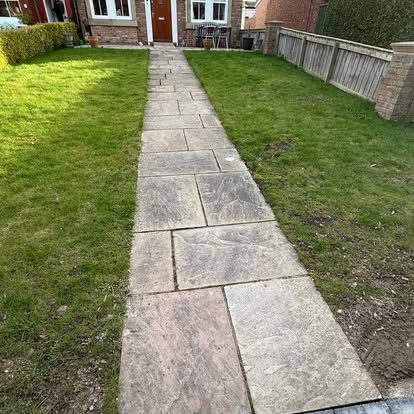 Stone path through a lawn before cleaning, darkened slabs