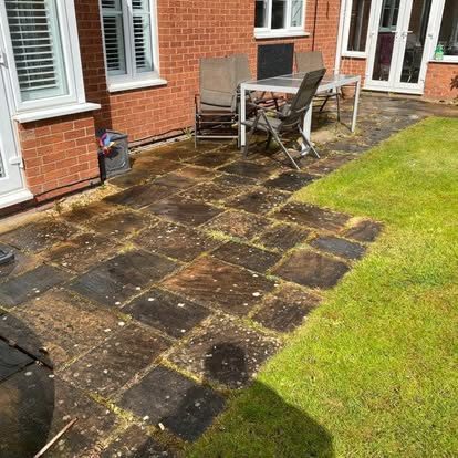Large sandstone patio before cleaning, heavy black organic spotting