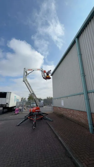 Cherry picker alongside the roofline of a commercial warehouse